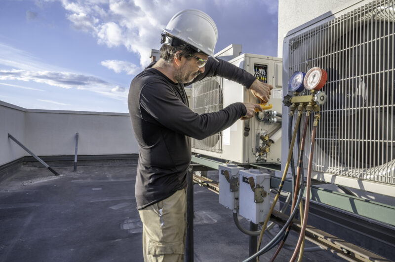 HVAC tech checking a commercial mini split air conditioner amps with a meter